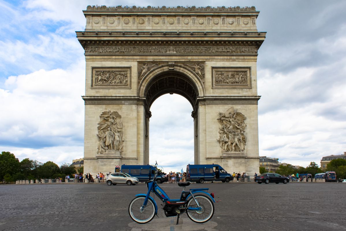 Une mobylette bleue devant l'Arc de Triomphe, à Paris.