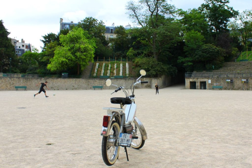 Une mobylette blanche au milieu de l'arene de Lutèce, à Paris.