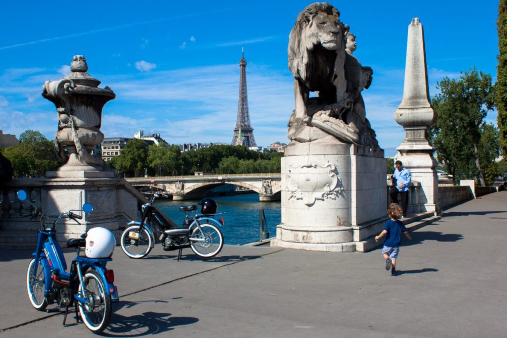 Deux mobylettes sur le pont Alexandre 3, devant la tour Eiffel.