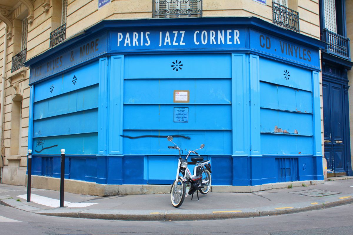 Une mobylette devant la façade bleu d'un magasin de musique jazz