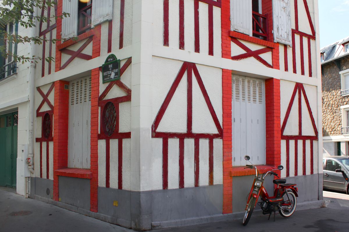 Une mobylette devant une maison à colombage rouge, à Paris.