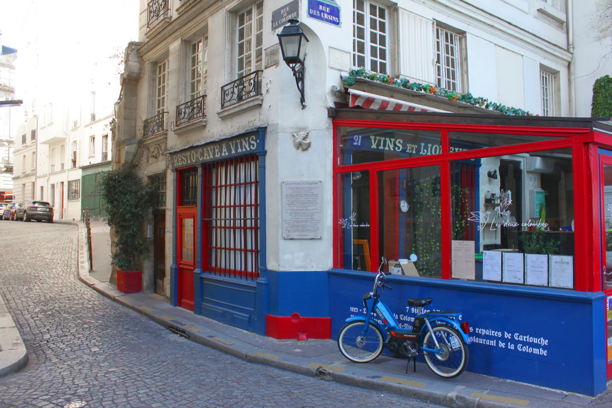 Une mobylette devant un restaurant à la façade bleu, blanc et rouge