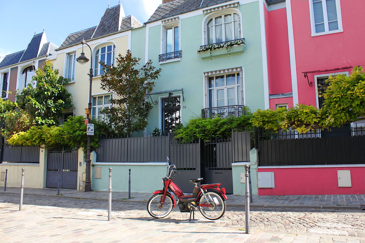 Une mobylette rouge devant une maison verte, dans la rue Dieulefoy, à Paris.