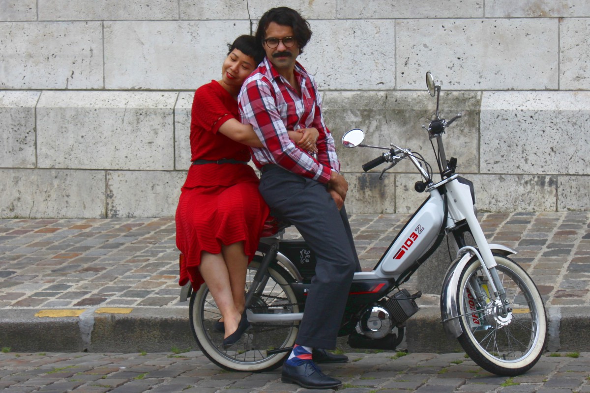 Un couple avec des habits vintage sur une mobylette dans une rue de Montmartre