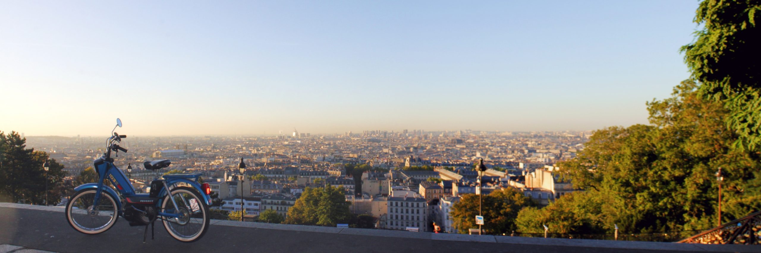 Une mobylette devant un panorama de Paris